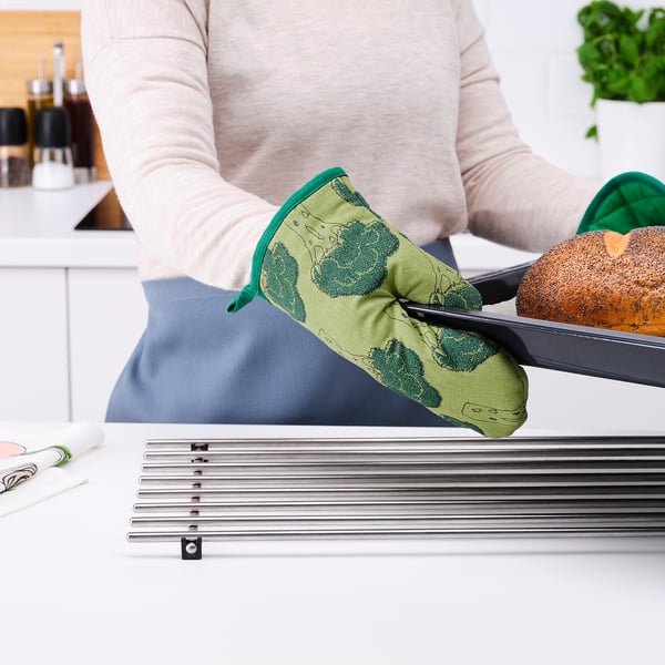 A person wearing TORVFLY oven mitts safely handles a baking tray with bread, demonstrating its heat protection.