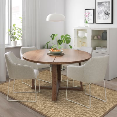 Modern dining set with TOSSBERG chairs, wooden table, jute rug, and oranges. Background: plants, cabinet.