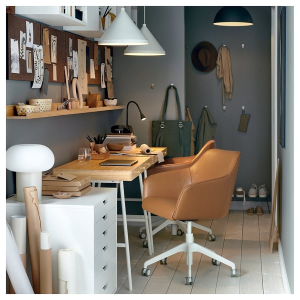 Home office setup: brown leather desk chair, wooden desk, shelves with designs, green walls, hanging coat, pendant lamps, wooden floor.