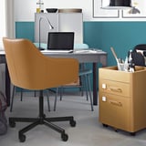 Home office setup: TOSSBERG chair, desk, cabinet. Ergonomic brown leather chair fits under desk. Blue-green wall storage.