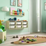 Playroom with TROFAST light wood storage shelves, colorful toys, books, and a beige rug.