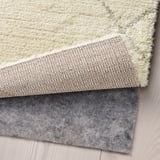 Three layered rugs: soft cream on top, textured beige in the middle, and dark gray felt underneath for grip, enhancing comfort and safety.