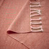 A soft, textured throw blanket with white fringe detailing. Its made of 100% wool.