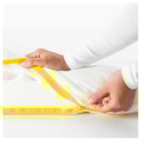 Hands adjusting zipper on a yellow-striped kids mattress, showcasing child-safe design.