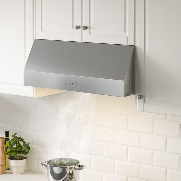 Stainless steel range hood in modern kitchen with led, herbs on stove, plant on counter.
