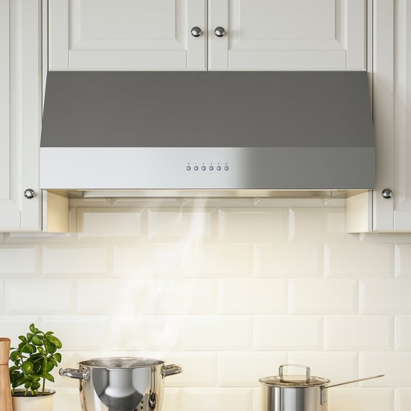 Stainless-steel range hood with led lights between white cabinets, efficient suction.