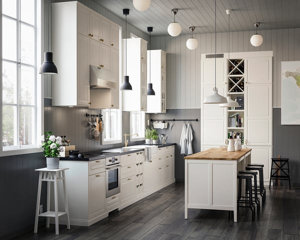 Modern kitchen with white cabinets, dark wood floors, stainless steel appliances, and hanging lights.