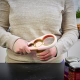 Person using UPPFYLLD jar opener, gripping a round container lid.