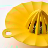 Bright yellow plastic lemon squeezer with a handle and multiple ridges to extract juice efficiently.