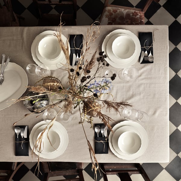 Elegant table set with white UPPLAGA porcelain, rustic design, black napkins, dried flowers centerpiece, on checkered floor.