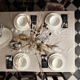 Elegant table set with white UPPLAGA porcelain, rustic design, black napkins, dried flowers centerpiece, on checkered floor.