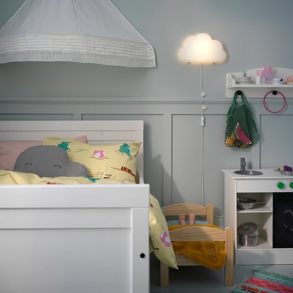 Childs room with white UPPLYST cloud lamp, pastel bedding, toy kitchen, and green mesh bag.