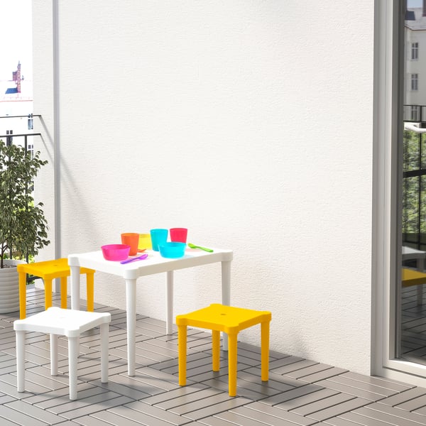 Bright kids play area with yellow and white stackable stools, a white table, and colorful cups and bowls, ideal for outdoor or indoor use.