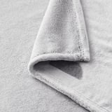 Soft, light gray fleece blanket folded neatly, showcasing cozy, plush texture for comfort.