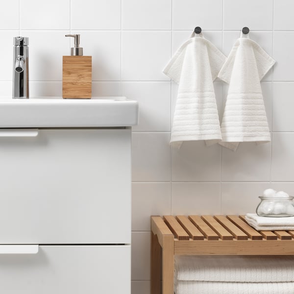 Modern bathroom with VÅGSJÖN towels on hooks, wooden towel rack, and soap dispenser beside chrome faucet.