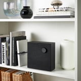 Bookshelf with black speaker, white vase, and decorative items.
