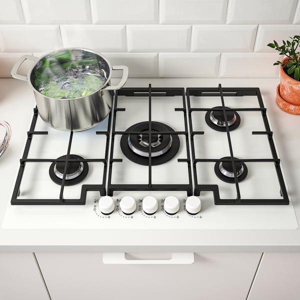 Gas stove with 5 burners, boiling vegetables, front knobs.