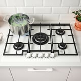 Gas stove with 5 burners, boiling vegetables, front knobs.
