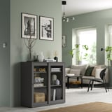 Modern mint living room with VIHALS black cabinet, gray couch, and large windows with plants.