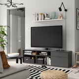Modern tv bench VIHALS, black, with large tv, drawers, & shelves. Decorative items, plant, & rug.