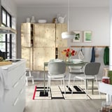 Modern kitchen VIHALS dining set. Light wood cabinet, white chairs surround glass table. Bright, minimalist design.