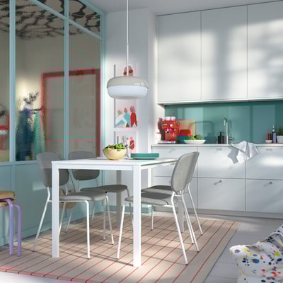 Bright kitchen with white VIHALS table and grey chairs, modern design, light blue accents, stainless sink, colorful rug, and hanging lamp.