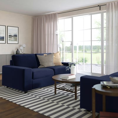 Cosy living room with blue VIMLE sofa, windows, coffee table, and bold rug.