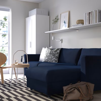 Modern living room with navy blue VIMLE sofa, white cabinet, black & white rug, & minimalist decor.