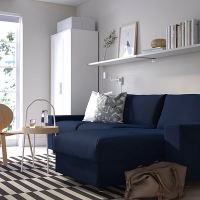Modern living room with large blue VIMLE sectional, sleek white shelves, patterned rug.