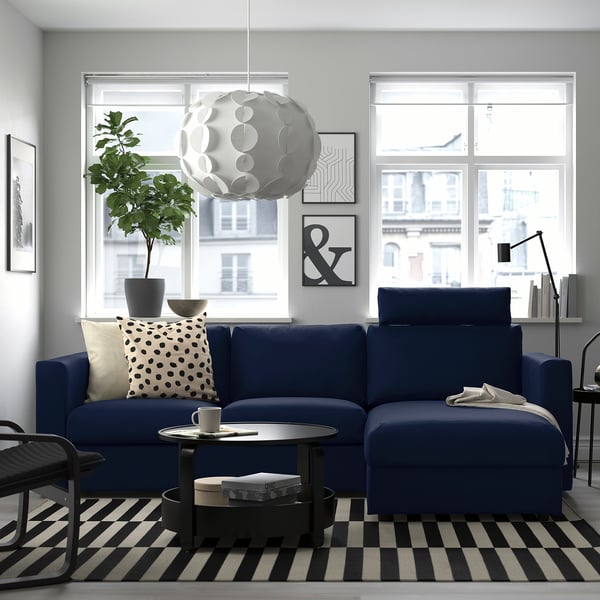 Cozy living room with blue VIMLE sectional sofa, large window, pendant lamp, black-and-white rug, and plants.