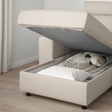 Beige sofa with storage. Lid open revealing pillows and blankets inside.