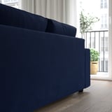 Modern navy sofa with chaise, near large windows and a potted plant.