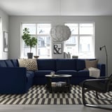 Modern living room with blue VIMLE sofa, throw pillows, coffee table, lamp, and large window.
