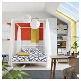 Modern bedroom with colorful VITARNA bed, yellow cushions, white curtains, and plant.