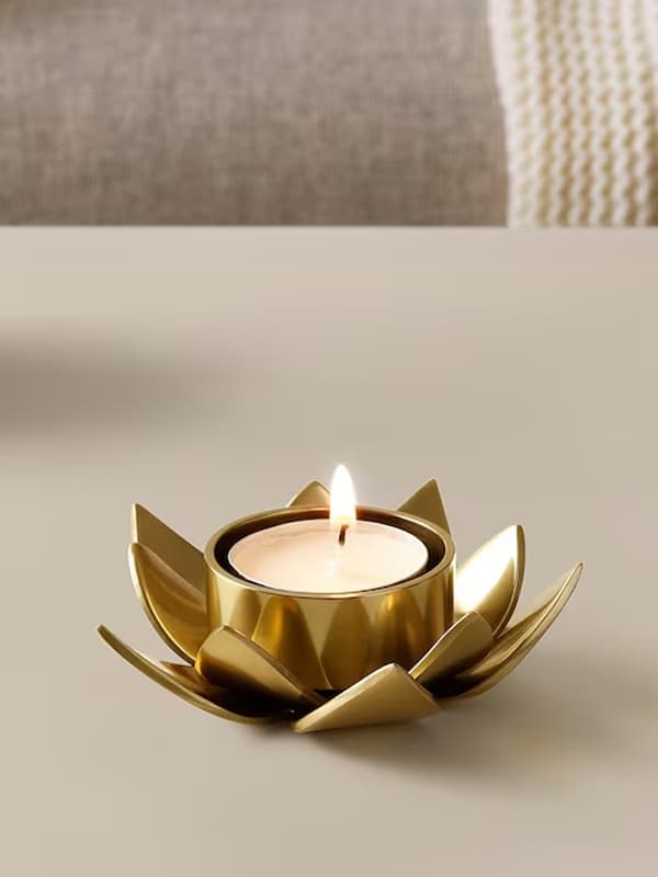 פמוט מוזהב נמוך בצורת עלי כותרת עם נר במרכזו