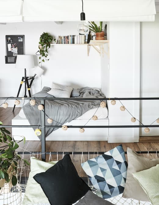 เตียงที่มีชั้นวางหนังสือด้านบน และหมอนอิงบนเปลญวนขนาดใหญ่