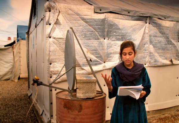 เด็กผู้หญิงกำลังอ่านหนังสือด้านหน้าดาวเทียมประดิษฐ์และที่พักชั่วคราว