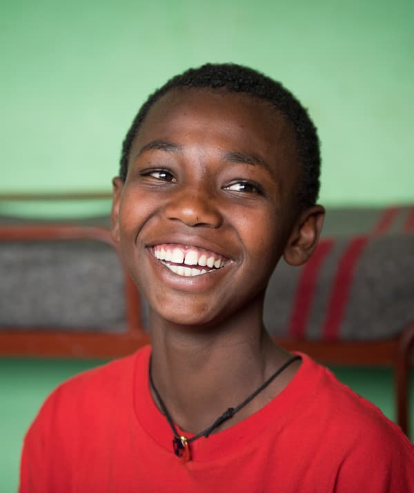 ภาพบุคคลของเด็กชายในเสื้อทีเชิ้ตสีแดงกำลังยิ้มอยู่