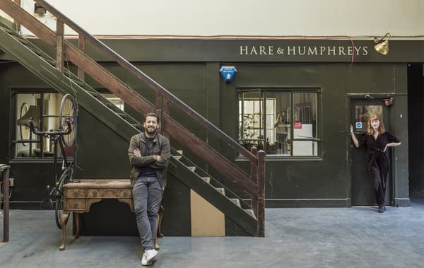 คนสองคนยืนอยู่ข้างนอกหน้าร้านเก่าและบันได