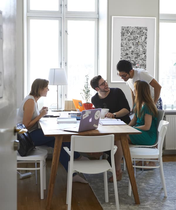 ผู้คนชุมนุมกันอยู่รอบๆ โต๊ะพร้อมด้วยแล็ปท็อปและสมุดจด