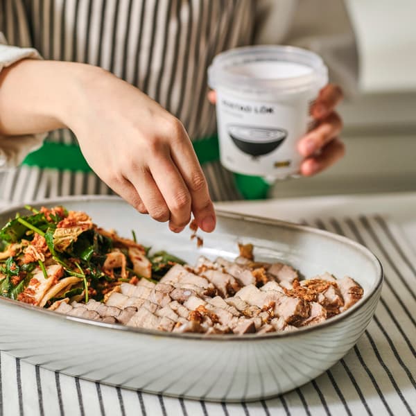 접시에 삼겹살과 겉절이를 함꼐 담아 양파 후레이크를 뿌리는 컷