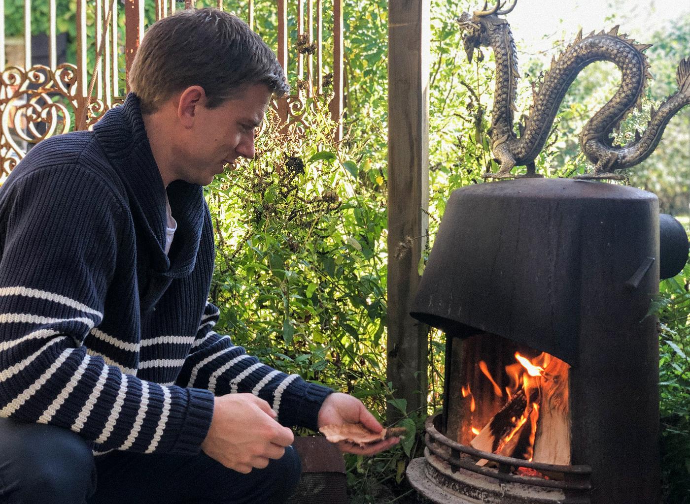 ผู้ชายที่สวมเสื้อกันหนาวสีน้ำเงินเข้มลายทางสีขาวกำลังง่วนอยู่กับการก่อไฟในเตาผิง