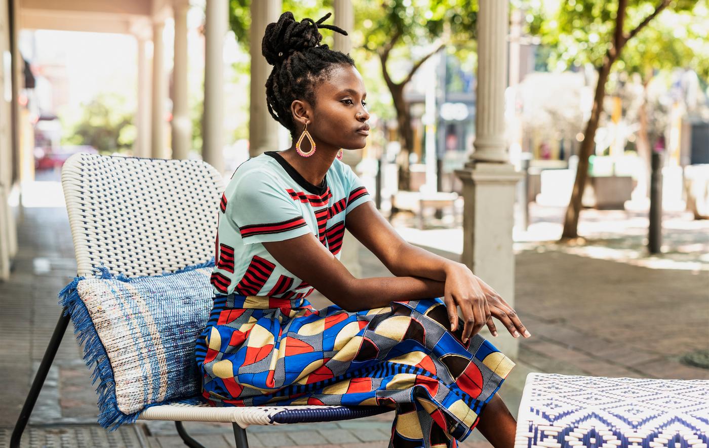 ผู้หญิงสวมเสื้อสีสดใสนั่งอยู่บนเก้าอี้โยกกลางแจ้ง