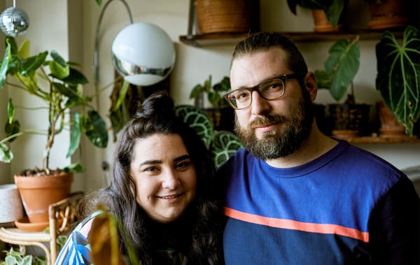 คู่รักวัยหนุ่มสาวในอพาร์ตเมนต์ในเมืองที่มีต้นไม้จำนวนมากอยู่ด้านหลัง