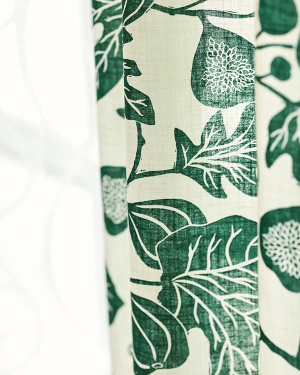 ม่านสองผืนแขวนอยู่ติดกัน ผืนหนึ่งเป็นผ้าฝ้ายโปร่งสีขาว อีกผืนเป็นลายใบไม้กราฟิกสีเขียว