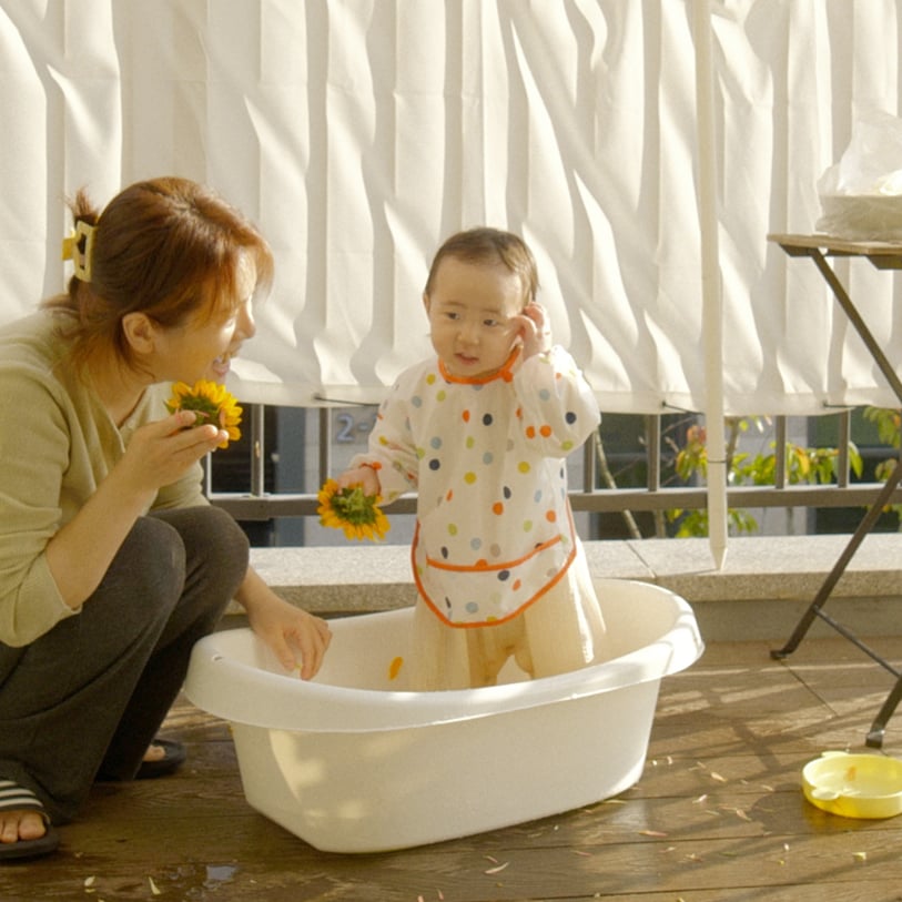 한 여성과 개 한 마리가 불 켜진 양초들이 가득한 테이블 앞에서 쉬고 있는 모습.