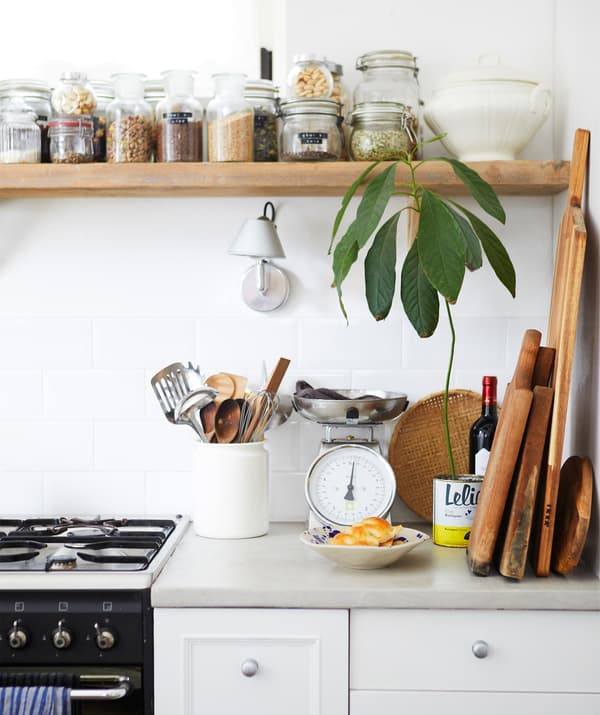 ท็อปครัวที่วางหม้อหุงข้าวและเขียงไม้ และโถใส่วัตถุดิบแห้งบนชั้นวางของทำด้วยไม้ด้านบน