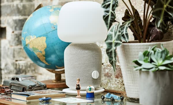 ตู้กระจกที่มีลูกโลก ต้นไม้กระถาง โคมไฟลำโพงสีขาว ตุ๊กตาเล็กๆ รถของเล่น โดมหิมะ และหนังสือจัดวางไว้ด้านบน