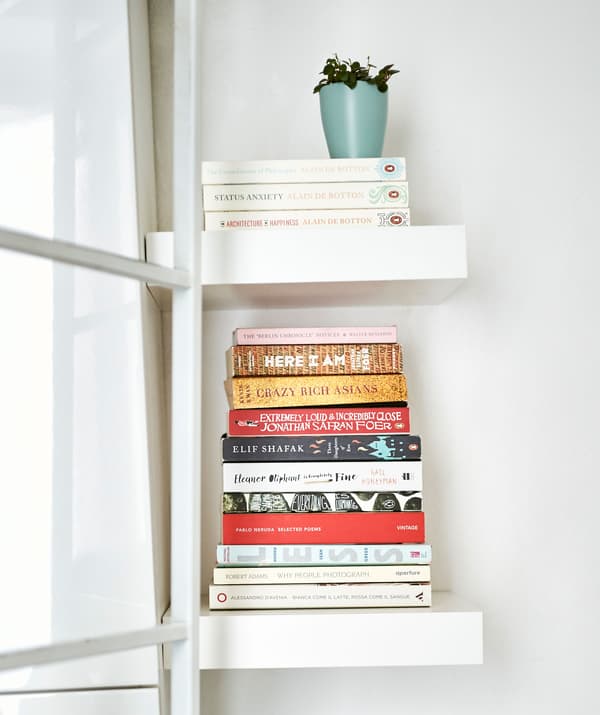 กองหนังสือบนชั้นวางสีขาวขนาดเล็ก