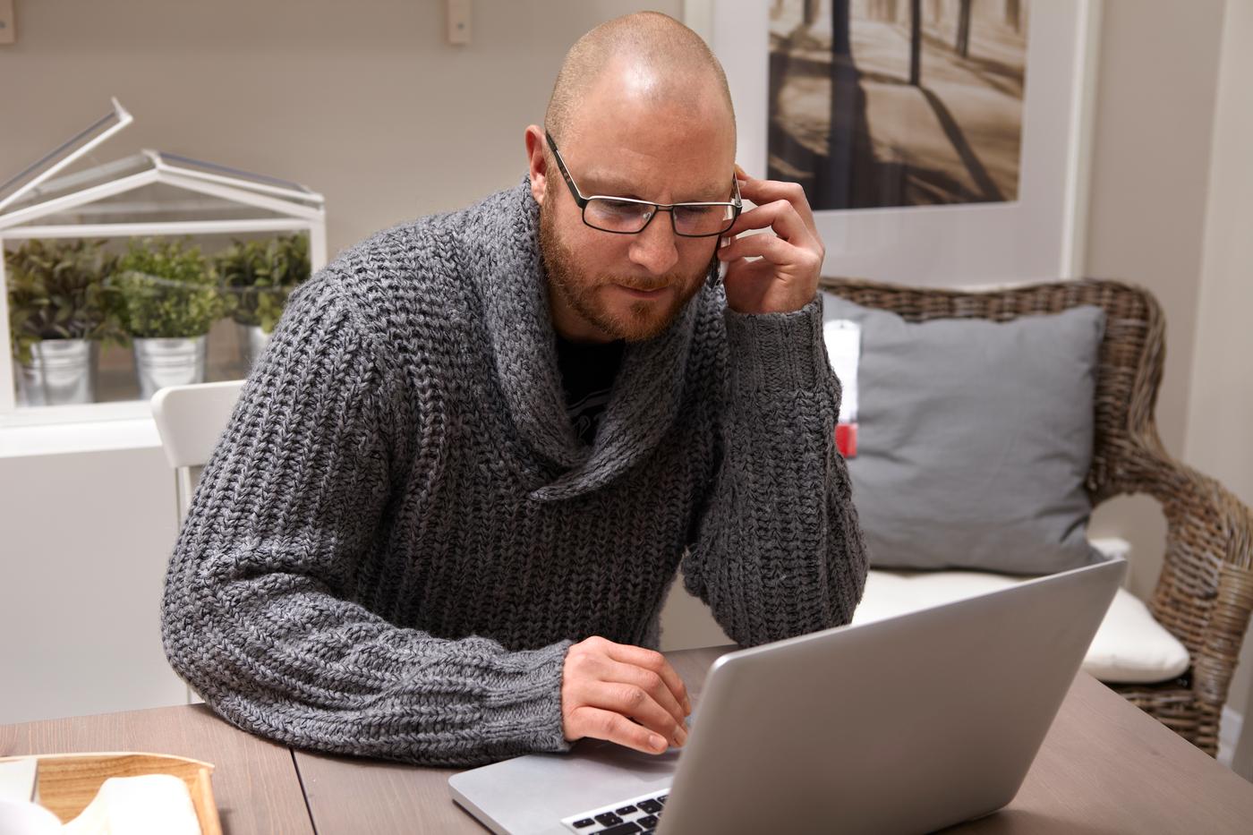 גבר מדבר בטלפון ועובד על מחשב נייד
